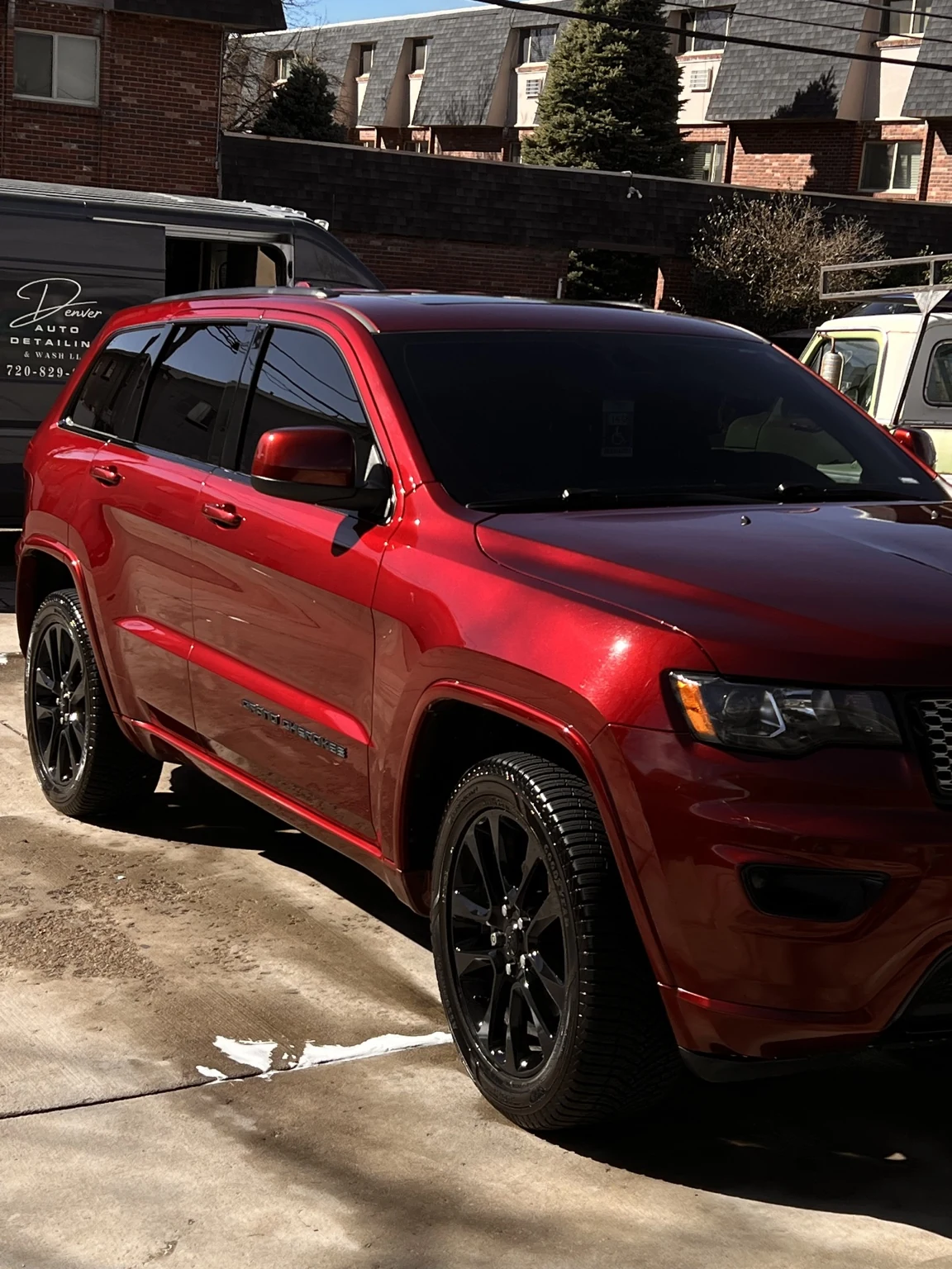 Red Jeep Grand Cherokee after detailing with the Denver Auto Detailing van visible in the background